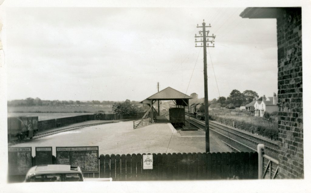 Livestock-loading facilities and goods siding at Rillington railway station, with a train passing on the main line.